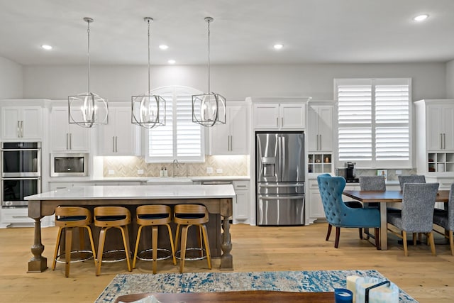 kitchen with stainless steel appliances, white cabinetry, a kitchen island, and a breakfast bar