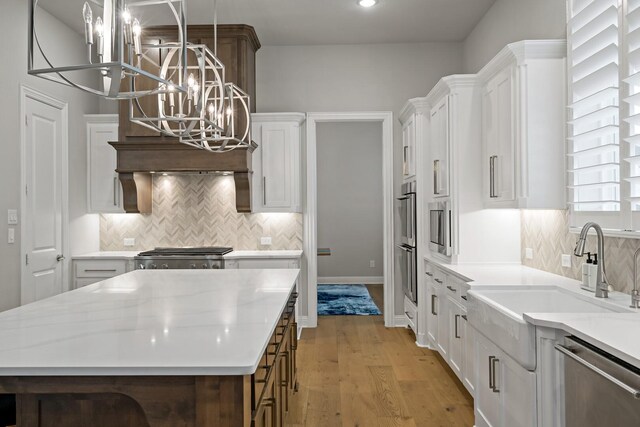 kitchen with pendant lighting, stainless steel appliances, a kitchen island, and white cabinets