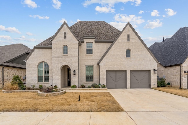 french provincial home with a garage and a front yard