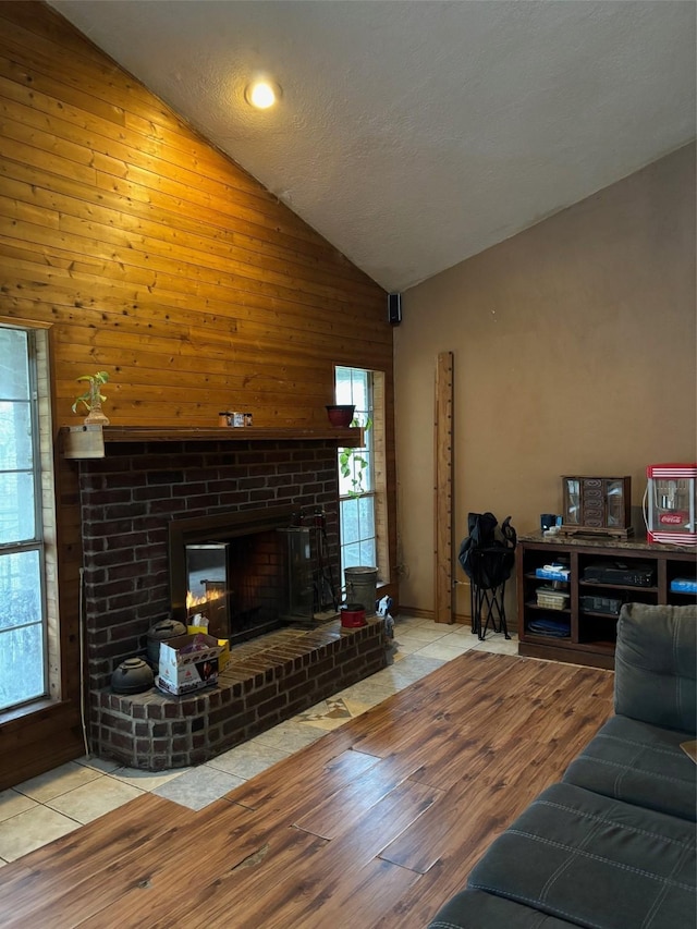 living room with high vaulted ceiling, a fireplace, and light hardwood / wood-style floors