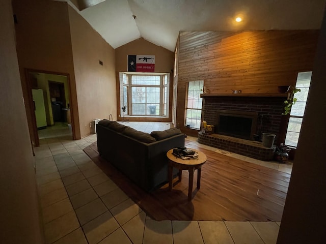 tiled living room with a brick fireplace and high vaulted ceiling