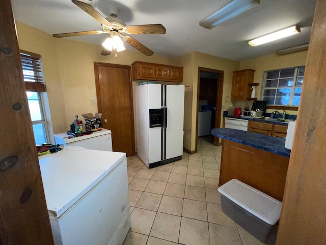 kitchen with ceiling fan, white appliances, washer and clothes dryer, and light tile patterned floors