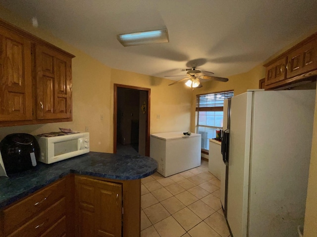 kitchen featuring ceiling fan, white appliances, kitchen peninsula, and light tile patterned floors