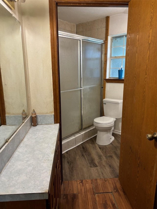 bathroom featuring vanity, hardwood / wood-style flooring, a shower with door, and toilet