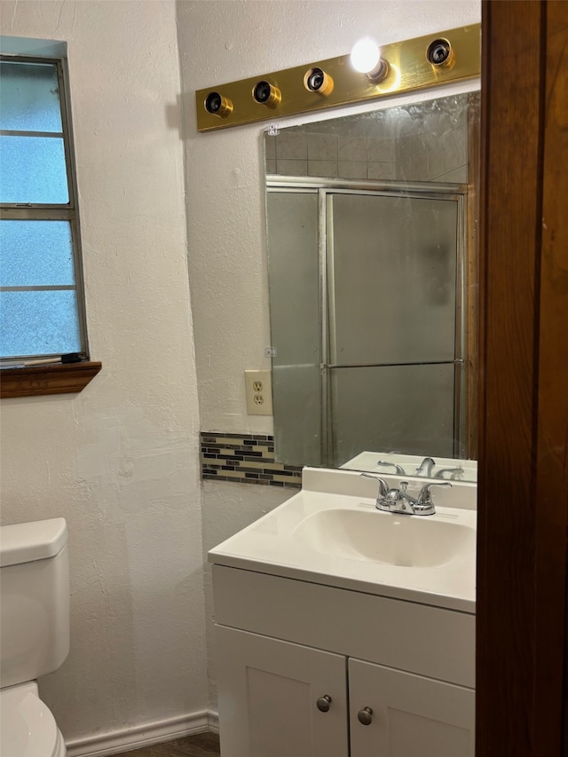 bathroom featuring vanity, toilet, and an enclosed shower