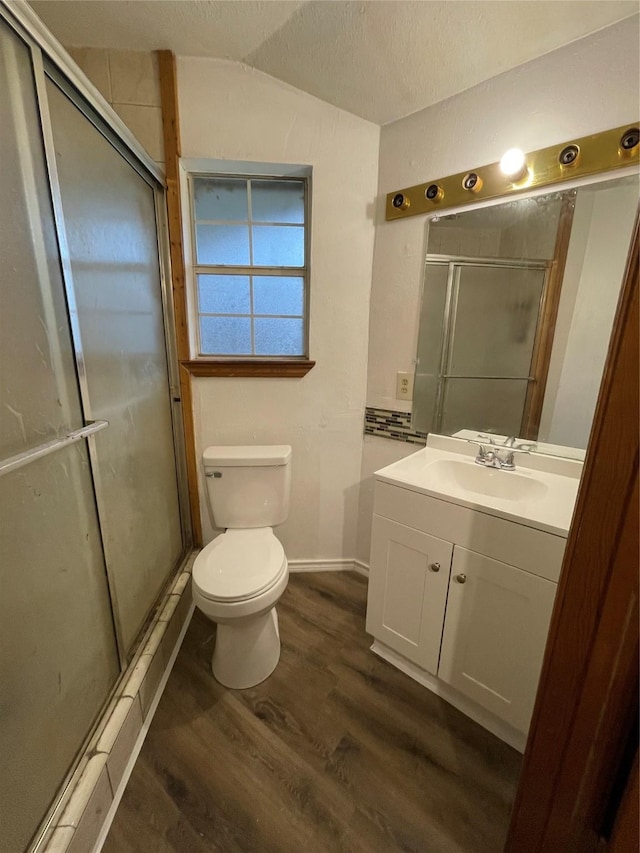 bathroom featuring hardwood / wood-style floors, a shower with shower door, vanity, toilet, and a textured ceiling