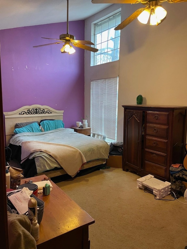 carpeted bedroom with a towering ceiling and ceiling fan