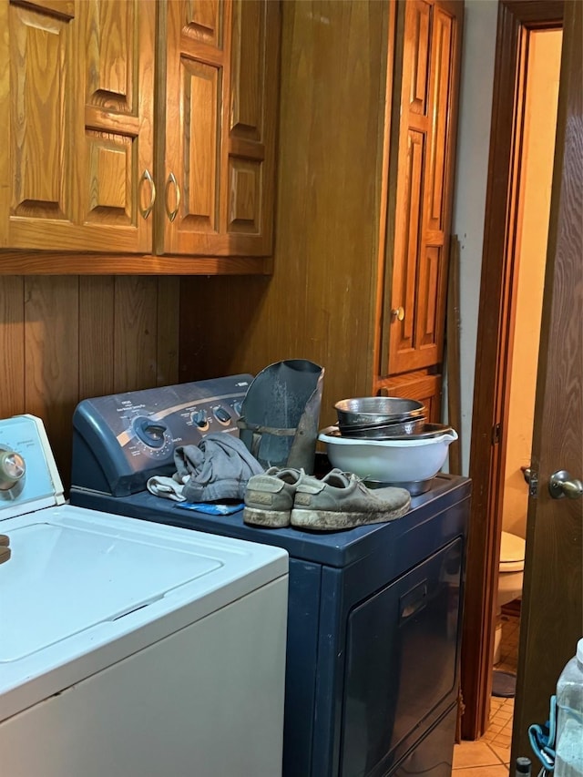 laundry area featuring cabinets, washing machine and dryer, and light tile patterned floors