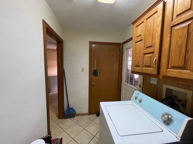 laundry area featuring washer / clothes dryer, light tile patterned floors, and cabinets