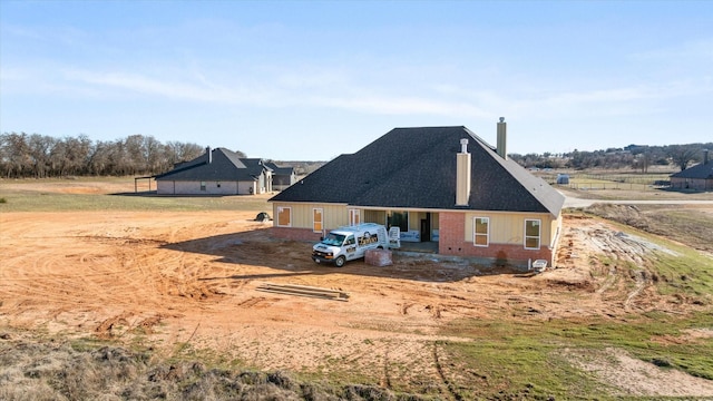 rear view of house featuring a chimney and brick siding