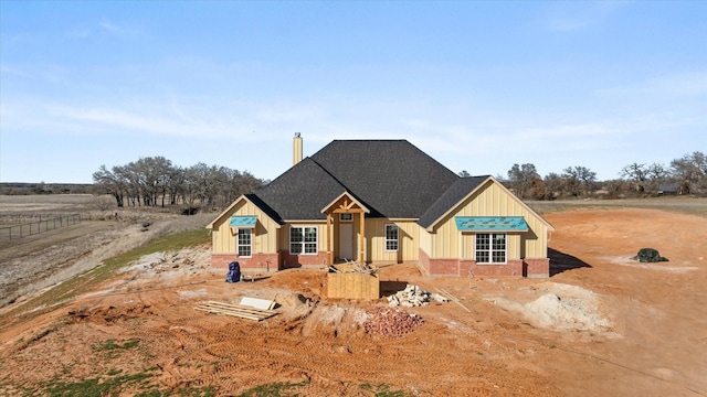 view of front of property with roof with shingles, board and batten siding, and brick siding