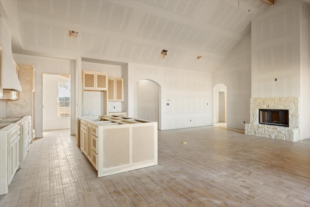 kitchen featuring open floor plan, light wood-type flooring, a fireplace, and arched walkways