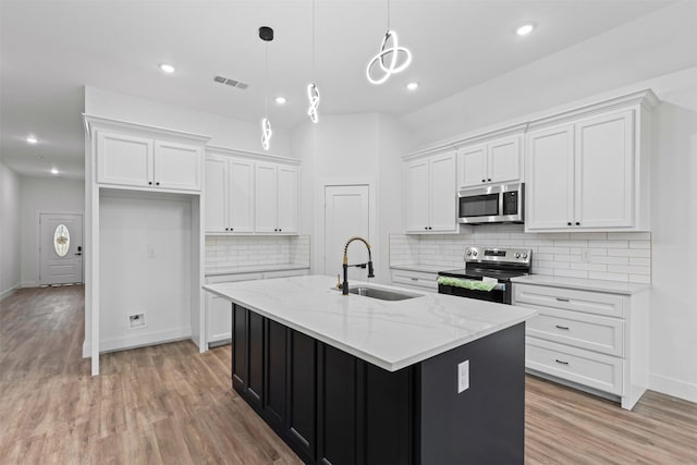 5065 Willie St, Fort Worth, TX 76105 - kitchen with stainless steel appliances, a sink, white cabinets, light wood-style flooring, and recessed lighting