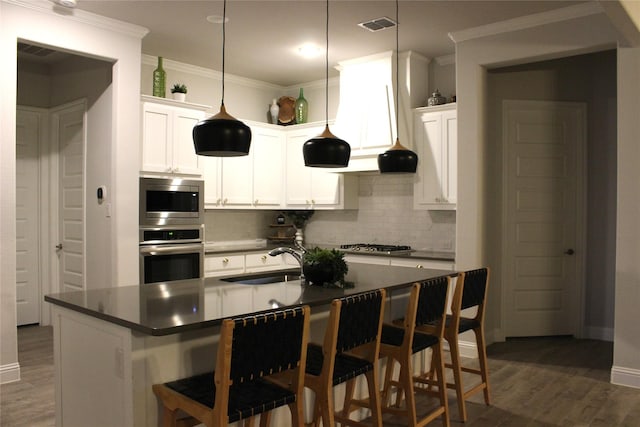 kitchen with white cabinetry, appliances with stainless steel finishes, sink, and a breakfast bar area