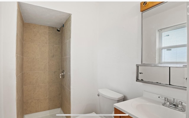 bathroom featuring vanity, toilet, and a tile shower