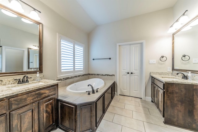 bathroom featuring vanity, vaulted ceiling, tile patterned floors, and a tub to relax in