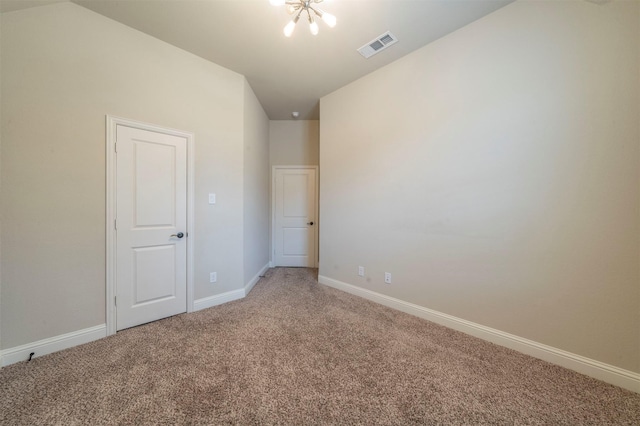 spare room with carpet floors and an inviting chandelier