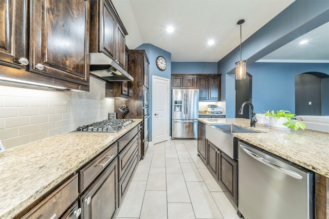 kitchen featuring decorative light fixtures, sink, stainless steel appliances, light stone countertops, and dark brown cabinets