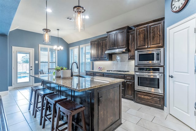 kitchen featuring pendant lighting, stainless steel appliances, a kitchen island with sink, and a breakfast bar area