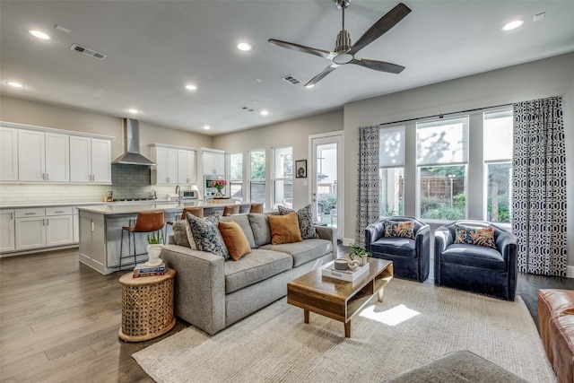 living room featuring ceiling fan, visible vents, dark wood-type flooring, and recessed lighting