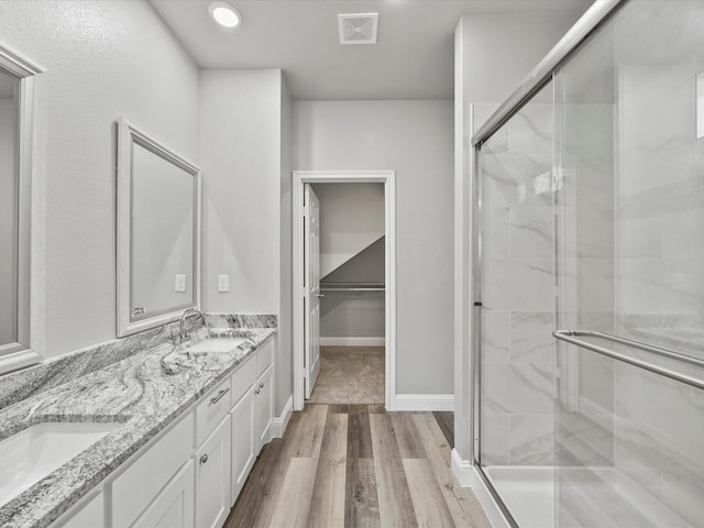 bathroom with walk in shower, vanity, and hardwood / wood-style flooring