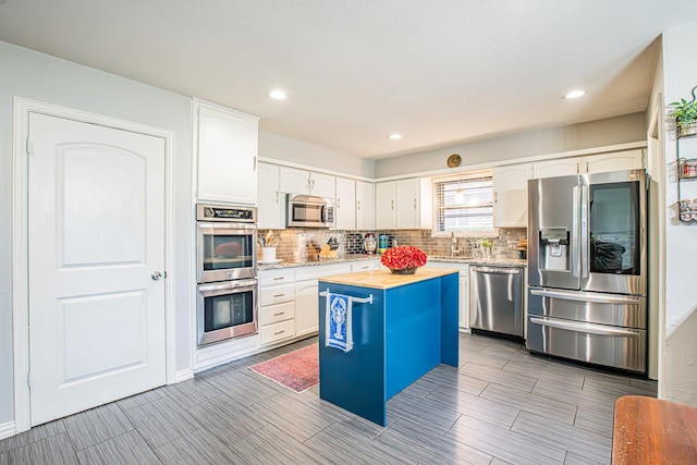 kitchen featuring white cabinetry, appliances with stainless steel finishes, a kitchen island, and backsplash