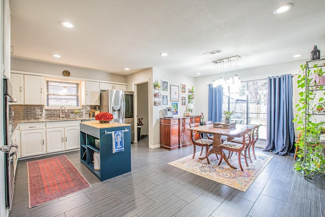 kitchen featuring sink, white cabinetry, hanging light fixtures, plenty of natural light, and a kitchen island