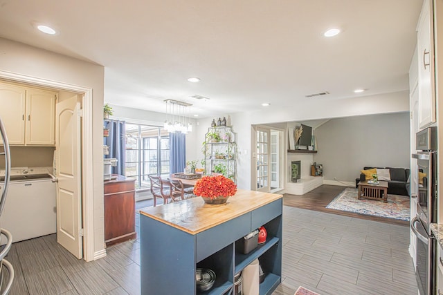 kitchen with butcher block countertops, white cabinetry, double oven, a kitchen island, and pendant lighting