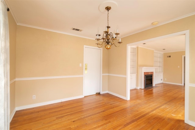 interior space featuring crown molding, hardwood / wood-style flooring, built in shelves, and an inviting chandelier