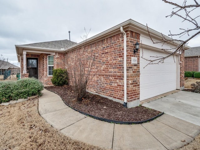 view of front facade featuring a garage, concrete driveway, brick siding, and roof with shingles