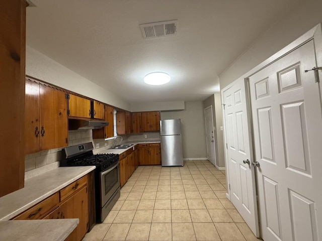 kitchen with light tile patterned floors, stainless steel appliances, sink, and backsplash