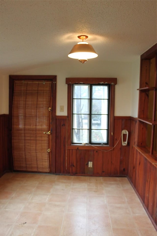 interior space featuring wooden walls and a textured ceiling