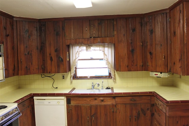 kitchen with sink, tile counters, dishwasher, decorative backsplash, and stove