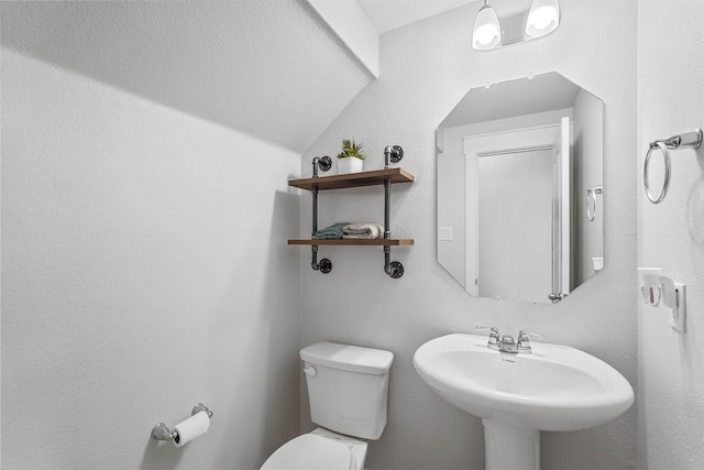 bathroom with vaulted ceiling, toilet, and sink