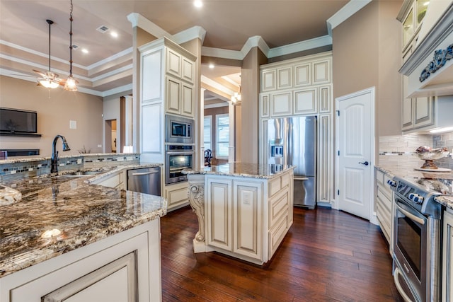 kitchen with sink, decorative light fixtures, a center island, appliances with stainless steel finishes, and light stone countertops