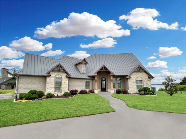 view of front of house with a front lawn, metal roof, stone siding, and a standing seam roof
