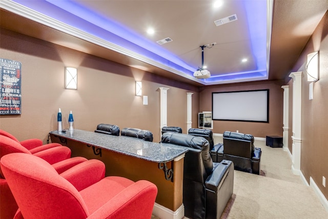 home theater featuring a raised ceiling, light carpet, and ornate columns