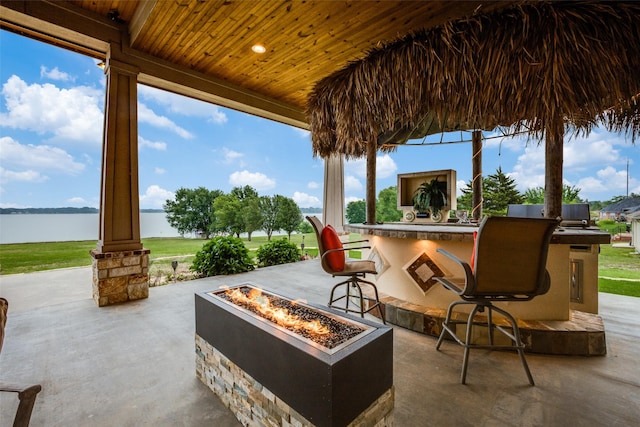 view of patio / terrace featuring a water view, a bar, and a fire pit