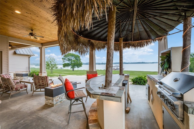 view of patio / terrace featuring exterior kitchen, a water view, a grill, and ceiling fan