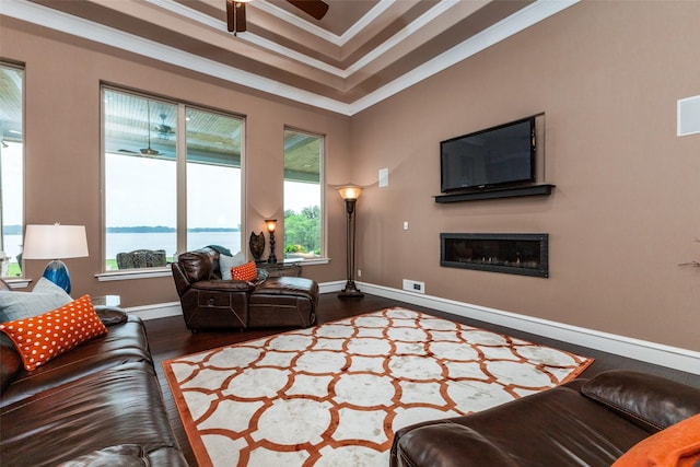 living room with a tray ceiling, hardwood / wood-style flooring, ornamental molding, and ceiling fan