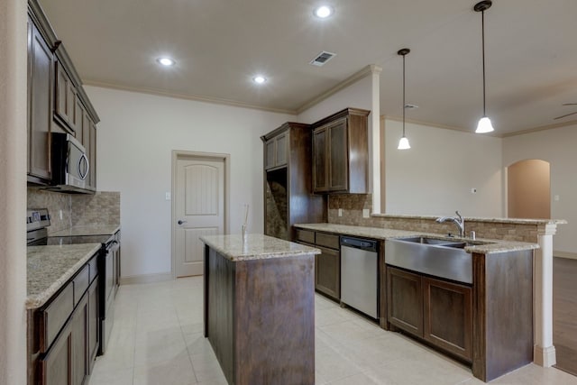 kitchen with appliances with stainless steel finishes, decorative light fixtures, sink, a center island, and dark brown cabinets