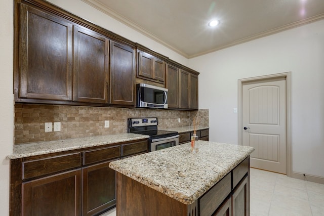 kitchen featuring dark brown cabinetry, crown molding, a center island, stainless steel appliances, and light stone countertops