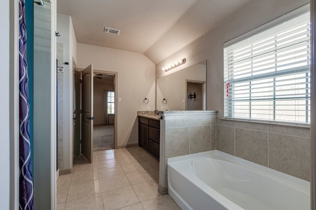 bathroom with tile patterned flooring, vanity, a washtub, and a healthy amount of sunlight