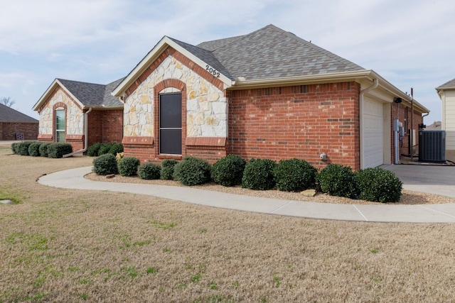 view of front of house with central AC unit, a garage, and a front lawn