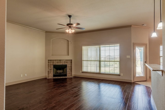 unfurnished living room with a tiled fireplace, crown molding, dark hardwood / wood-style floors, and ceiling fan