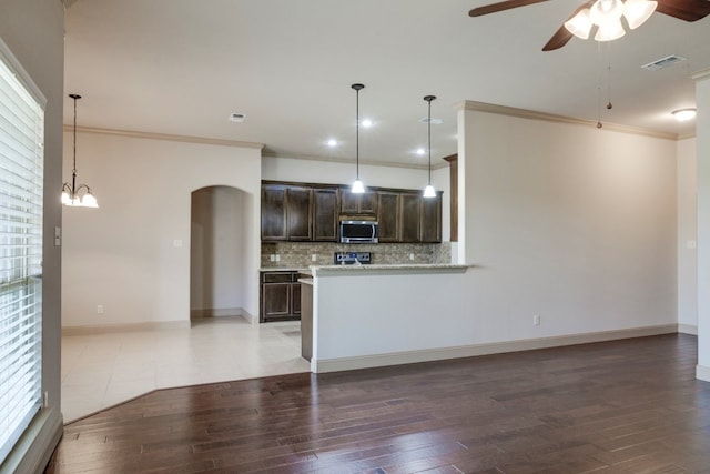 kitchen with hanging light fixtures, wood-type flooring, dark brown cabinets, and backsplash