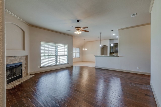 unfurnished living room featuring ornamental molding, dark wood-type flooring, a tile fireplace, and ceiling fan