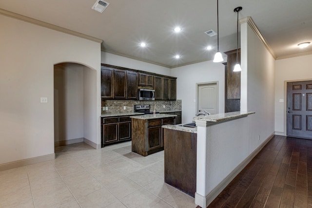 kitchen with light stone counters, decorative light fixtures, ornamental molding, kitchen peninsula, and backsplash