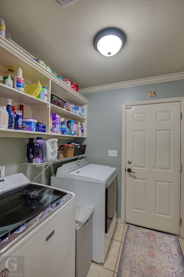 washroom with light tile patterned flooring, ornamental molding, separate washer and dryer, and a textured ceiling