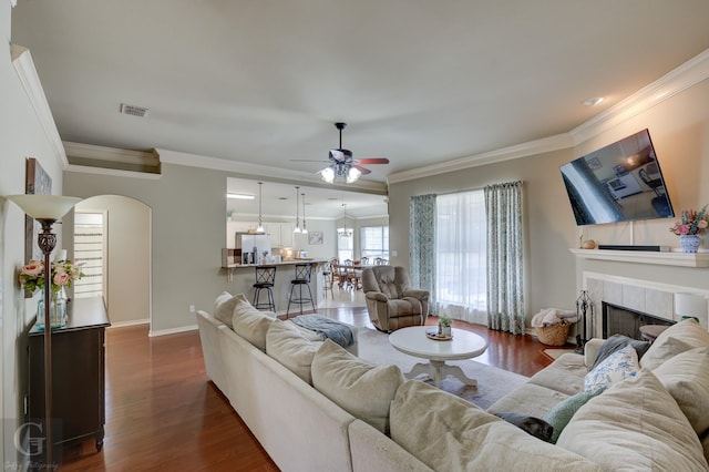 living room with ornamental molding, dark hardwood / wood-style flooring, and a tiled fireplace